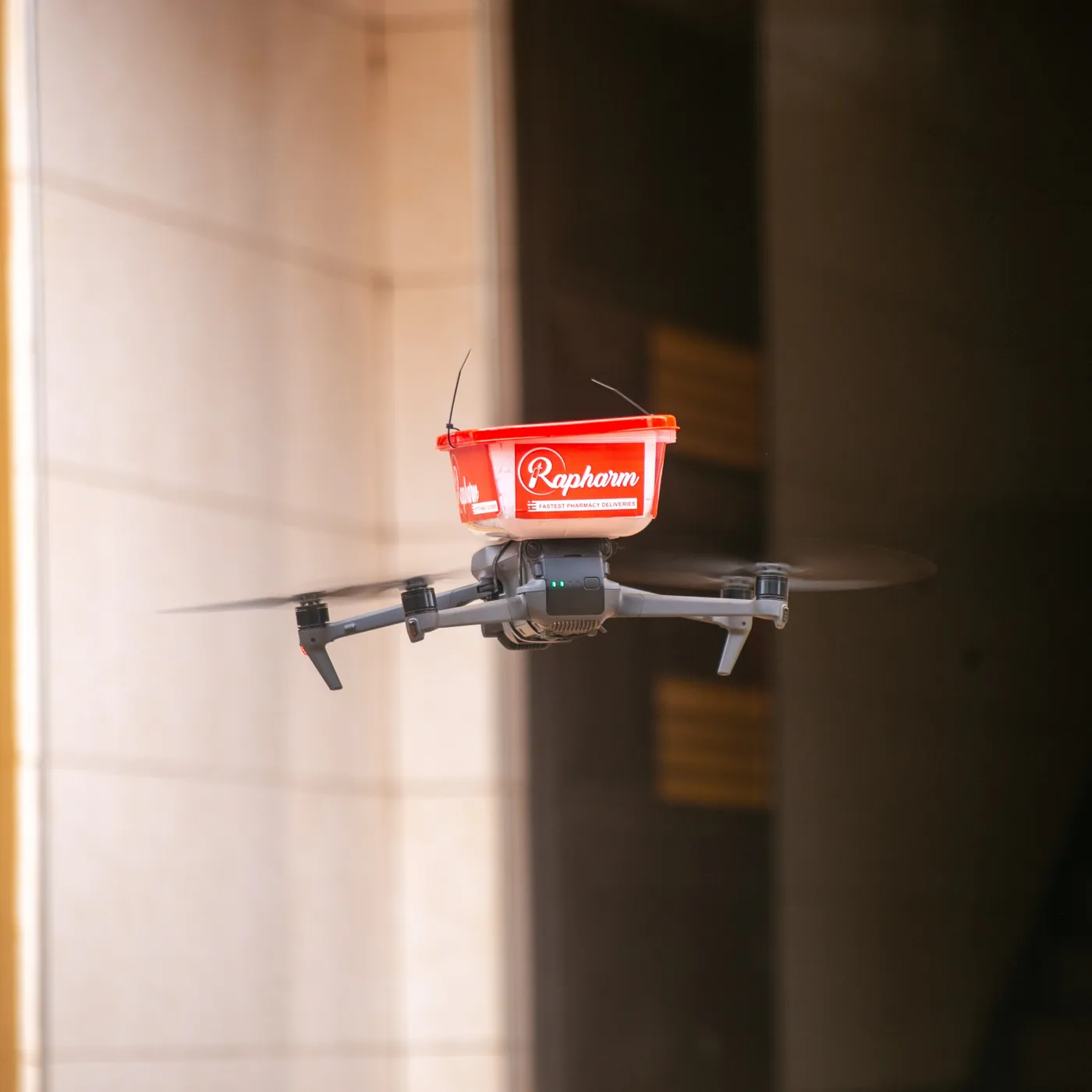 A Rapharm delivery drone in flight, carrying a branded medicine package